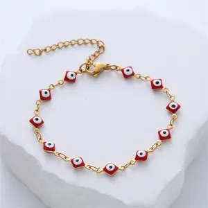 Detailed view of a gold stainless steel bracelet with red evil eye enamel charms.