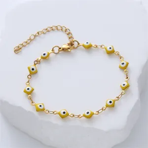 Close-up of yellow evil eye stainless steel bracelet on white rock prop
