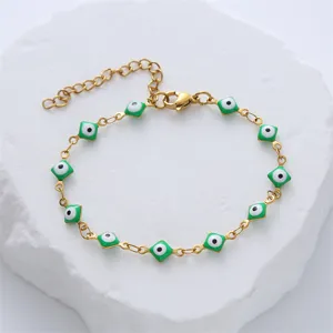 Detail view of a Turkish Evil Eye gold stainless steel bracelet with green enamel charms.