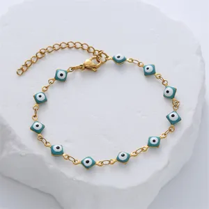 Close-up of gold stainless steel bracelet with square blue evil eye enamel charms