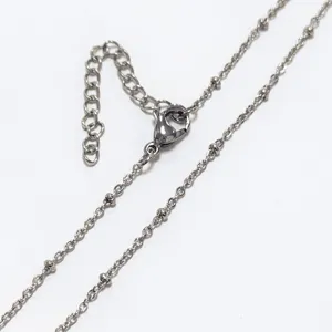 Close-up of stainless steel bean chain necklace showing clasp and extender details