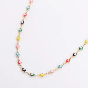 Primo piano di ciondoli evil eye in smalto colorato su una collana in acciaio dorato