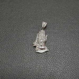 Detalle de colgante de manos en oración de acero inoxidable sobre cuero negro liso