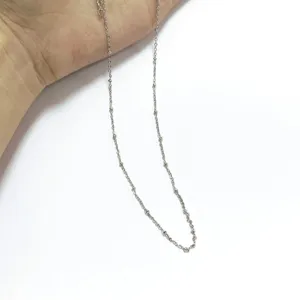 Close-up macro view of minimalist silver stainless steel bead chain necklace texture