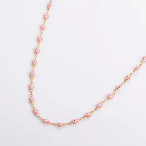 Dettaglio collana minimalista in acciaio inossidabile dorato con perline malocchio rosa