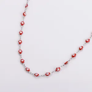 Dettaglio della collana in acciaio inox con mani di Hamsa rosse e ciondoli malocchio.