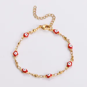 Dettaglio di un bracciale in acciaio inossidabile dorato con ciondoli occhio rosso