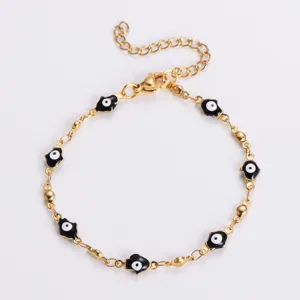 Dettaglio di un bracciale in acciaio inossidabile dorato con mani di Hamsa nere
