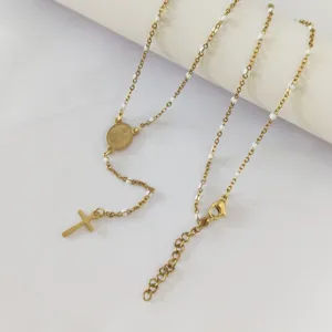 Detailed view of gold stainless steel religious necklace with white enamel beads and cross