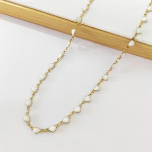 Close-up of white enamel heart charms on a gold-plated stainless steel chain necklace