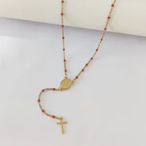 Detail of gold stainless steel rosary necklace with red beads and cross pendant