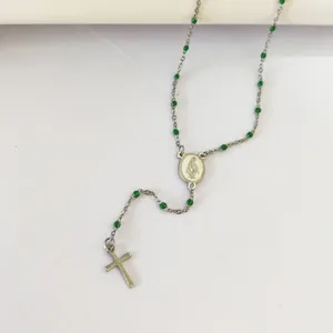 Close-up of silver-tone religious rosary necklace with green enamel beads and cross