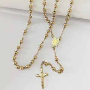 Dettaglio di una collana rosario in acciaio inossidabile dorato con crocefisso di cristallo.