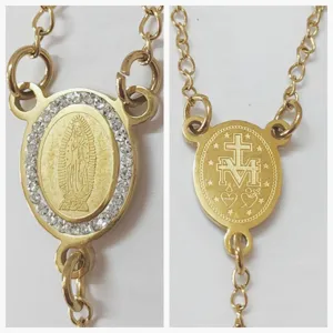 Vista dettagliata del ciondolo Madonna in oro con cristalli e incisione su entrambi i lati.