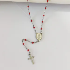 Detailed view of religious rosary necklace featuring red oil-dropped beads and silver cross