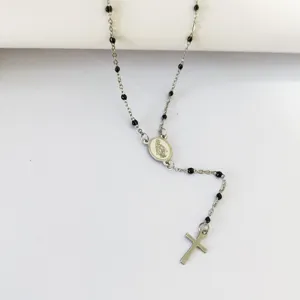 Detail of a stainless steel rosary necklace featuring black beads and a cross pendant