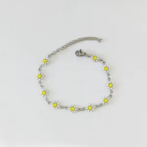 Vista dettagliata di un bracciale in acciaio argento con piccole margherite bianche e gialle.