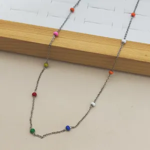 Macro detail of stainless steel necklace featuring vibrant rainbow enamel beads and slim chain