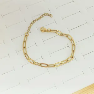 Close-up of a gold-colored stainless steel paperclip link bracelet on a white tray