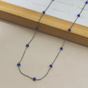 Detail shot of stainless steel necklace with blue beads on wooden jewelry display stand.