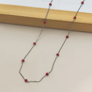 Detail of stainless steel necklace featuring vibrant red oil-drop beads on a delicate chain.