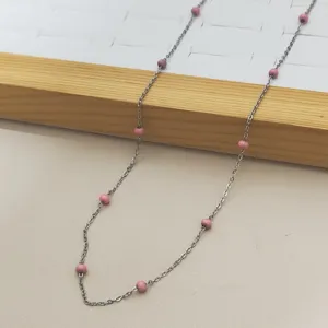 Detail shot of stainless steel necklace with pink enamel beads in bohemian style
