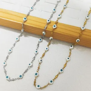 Detalle de collares de acero inoxidable con cuentas blancas de ojo turco en oro y plata
