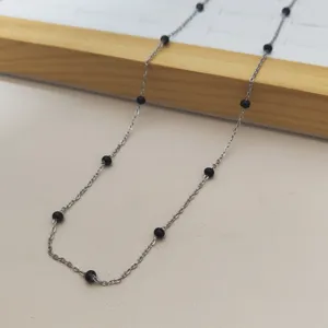 Detailed view of stainless steel chain necklace with minimalist black resin beads