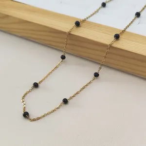 Close-up of golden stainless steel chain necklace with black enamel beads