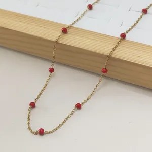Close-up of gold stainless steel necklace with red enamel beads in Bohemian style.