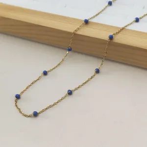 Close-up of a minimalist gold stainless steel necklace with delicate blue enamel beads