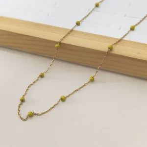Detailed view of a gold stainless steel necklace with vibrant olive green enamel beads