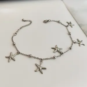 Close-up detail of stainless steel starfish anklet with beach-themed charms