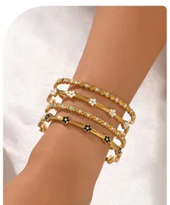 Detailopname van vergulde armbanden met emaille bloemen en glanzende strass