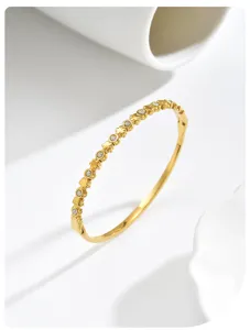 Detailopname van een minimalistische goudkleurige armband met klavermotieven en kristallen