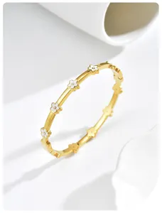 Detailweergave van een goudkleurige armband met witte emaille bloemen en kristallen