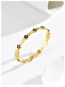 Detailopname van een elegante gouden armband met zwarte bloemen en kleine kristallen