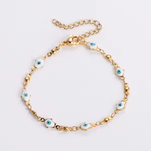 Dettaglio di un bracciale Hamsa in acciaio dorato con ciondoli occhio di Allah blu.