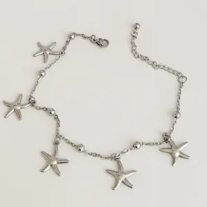 Detailed macro view of a silver stainless steel anklet featuring five starfish charms.