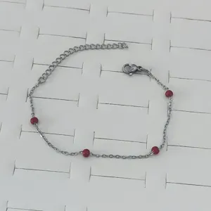 Detail of stainless steel bracelet with vibrant red drip oil round beads