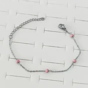 Silver stainless steel bracelet featuring four pink beads on a white jewelry display.