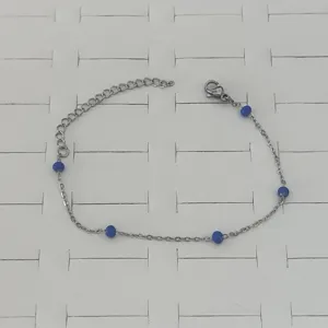 Close-up of a minimalist stainless steel chain bracelet with vibrant blue enamel beads