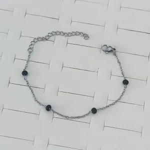 Detail shot of a minimalist stainless steel bracelet with black enamel bead accents
