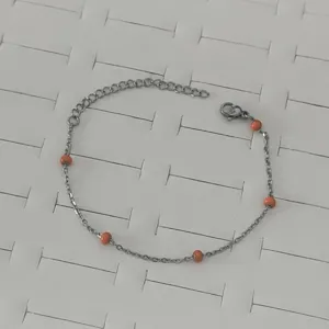 Detailed shot of a stainless steel bracelet with small vibrant orange enamel beads