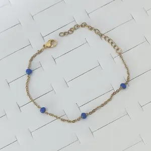Detailed view of gold stainless steel bracelet featuring vibrant blue enamel beads.