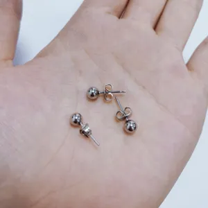 Nahaufnahme von minimalistischen silbernen Kugelohrsteckern aus Edelstahl in der Hand