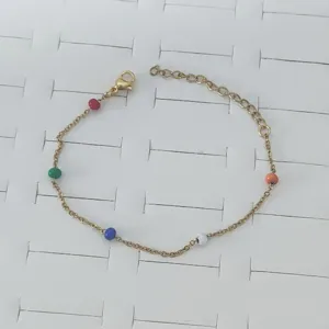 Detailed view of a gold stainless steel bracelet featuring vibrant multi-colored enamel beads