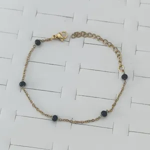 Detail view of gold stainless steel bracelet with blue enamel beads and lobster clasp