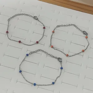 Three minimalist stainless steel chain bracelets with colorful enamel beads set on tray
