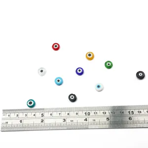 Flat round colorful evil eye glass beads shown with a ruler for size reference.